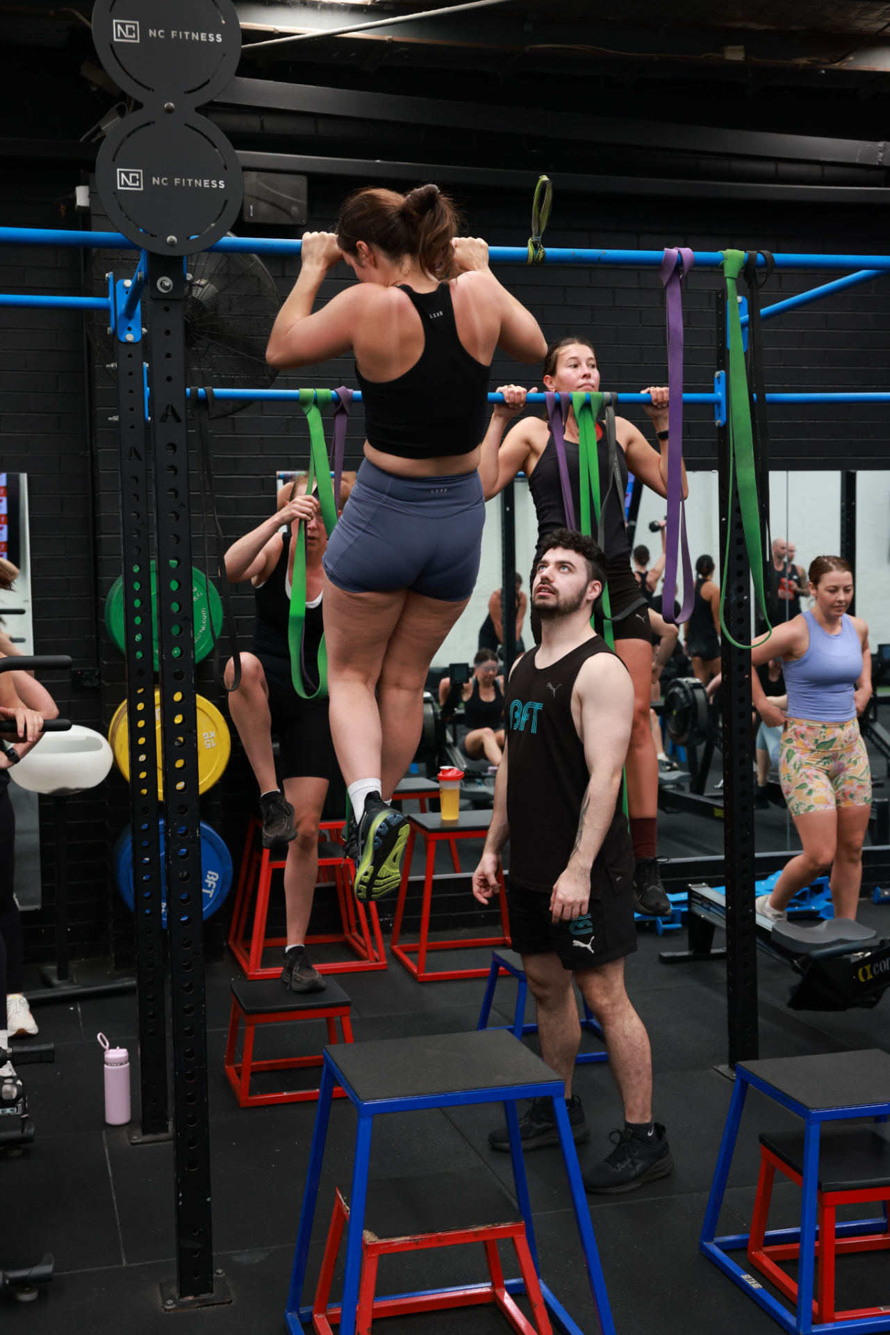 A BFT Abbotsford coach spotting a member during a pull up